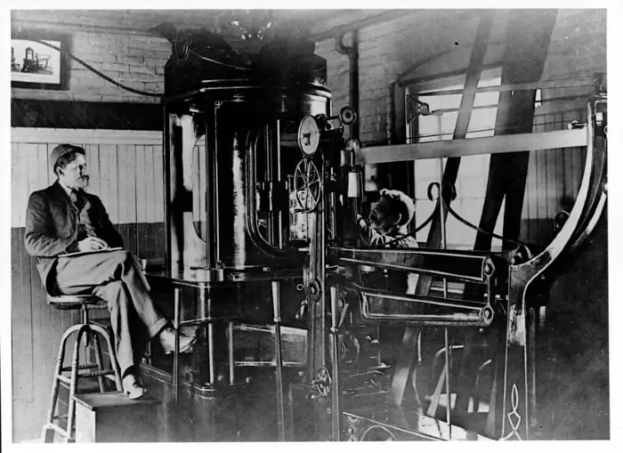 Um homem, possivelmente Frederick W. Taylor, observa um engenheiro trabalhando em Midvale Steel Company, na Filadélfia, em 1885. Kheel Center Cornell University.