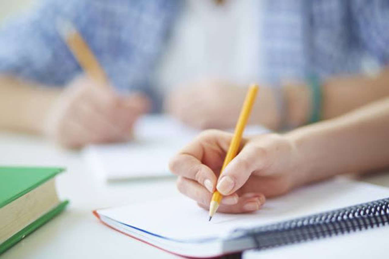 o-que-e-adverbio - mão segurando lápis e escrevendo em caderno